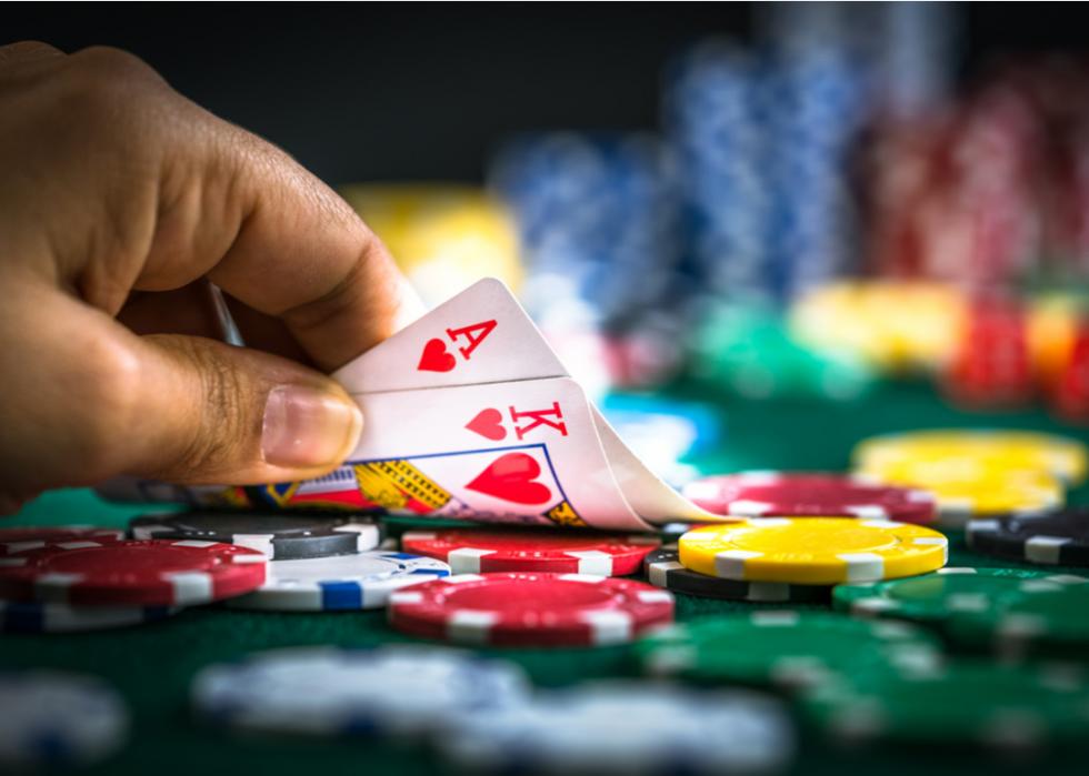 A closeup of a player at a poker table looking at their cards.